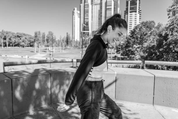Young girl smiles joyfully, walking through a lively downtown street on a sunny day.
