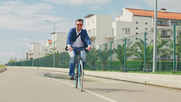 Businessman commute to work on bicycle on summer street. Happy man riding on bike on city street
