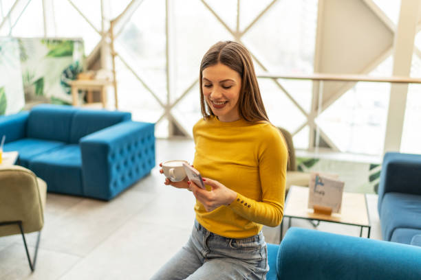 istock Young smiling woman texting on mobile phone at a cafe 2203110201