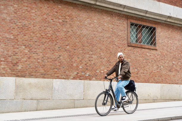 istock Stylish man riding bicycle in urban setting near brick wall 2203110301