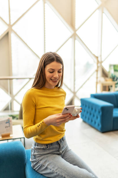 istock Young smiling woman texting on mobile phone at a cafe 2203110336