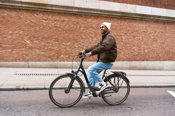 istock Stylish man riding bicycle in urban setting with brick wall background 2203110449