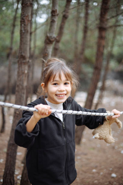 Little cheerful girl plays on vacation in the park at the playground. The child is having fun on the street on vacation. The child goes in for sports on simulators.
