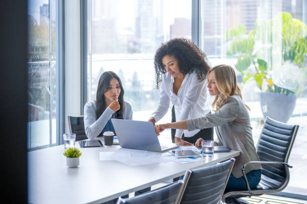 istock Three business  women meeting. They are discussing something while looking at a laptop computer. 2203125657
