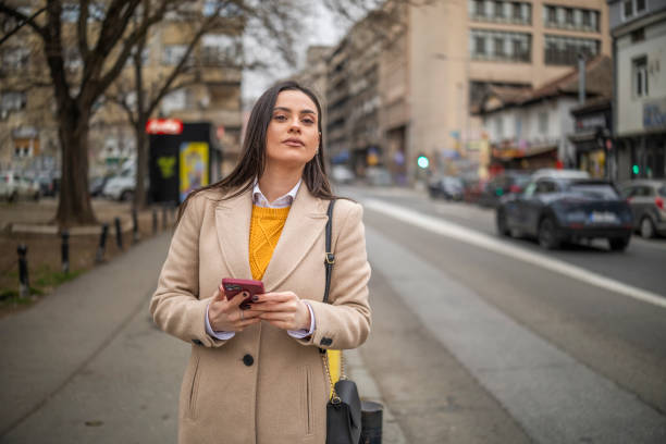 istock Adorable girl - tourist using maps app on her mobile phone while travelling and looking for right direction. 2203125998