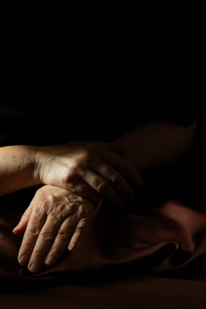 istock hands of an elderly woman on a dark background 2203127539