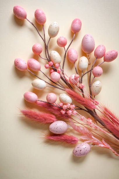 istock Easter flat lay composition with bouquet of pastel pink and beige Easter eggs on yellow background with copy space 2203127978