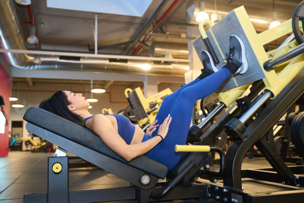istock Woman exercising on leg press machine in gym 2203134411