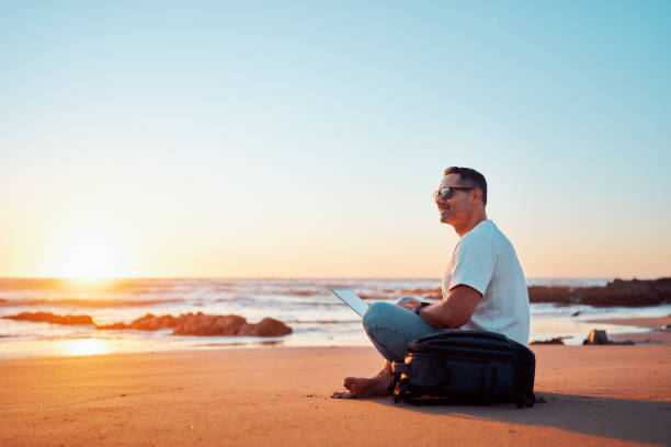 istock Freelancer working on laptop at sunset on beach 2203136425
