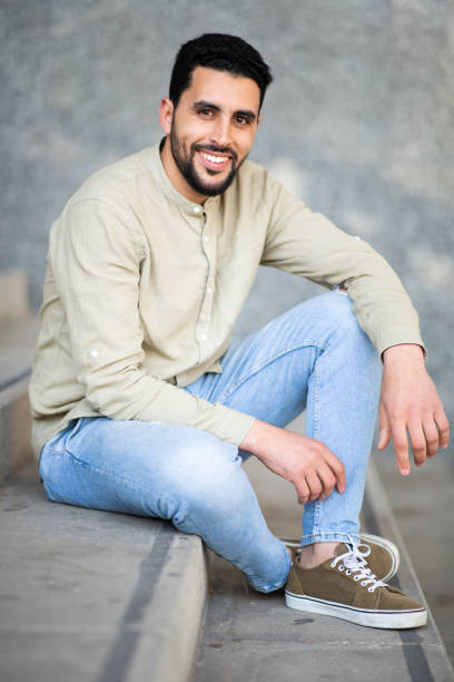 istock Confident young middle eastern man sitting on steps and smiling 2203139491