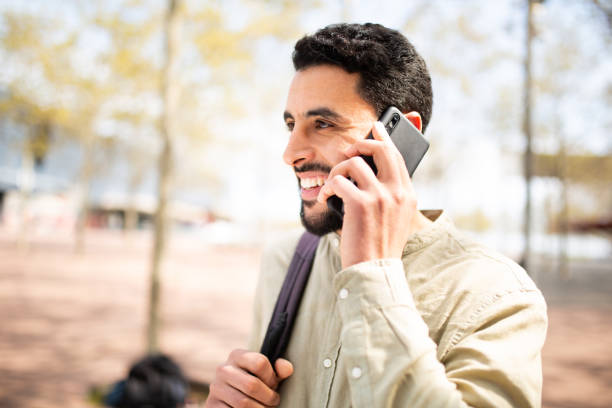 istock Handsome young arabic man walking outside talking on mobile phone 2203139540