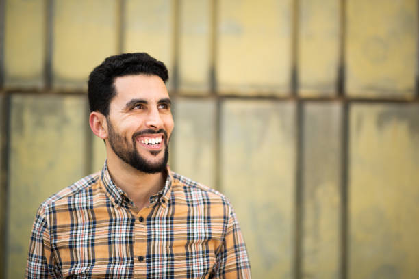 istock Handsome young arabic man standing against yellow wall looking away and smiling 2203139736