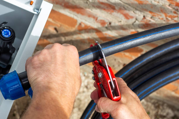 istock Installation of a drip irrigation system for a garden. A man cuts a HDPE pipe with scissors 2203140010