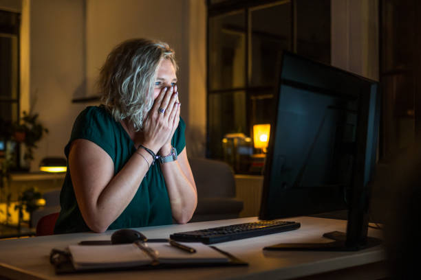 istock Mid Adult Woman Working Late at Computer in Dark Home Office 2203140177