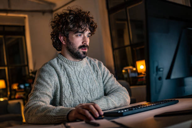 Focused Young Hispanic Male Working on Desktop in Cozy Home Office A young Hispanic male in his 20s works intently on a computer in a cozy home office, softly illuminated by warm, ambient lighting during nighttime. unpredictable stock pictures, royalty-free photos & images Focused Young Hispanic Male Working on Desktop in Cozy Home Office A young Hispanic male in his 20s works intently on a computer in a cozy home office, softly illuminated by warm, ambient lighting during nighttime. unpredictable stock pictures, royalty-free photos & images