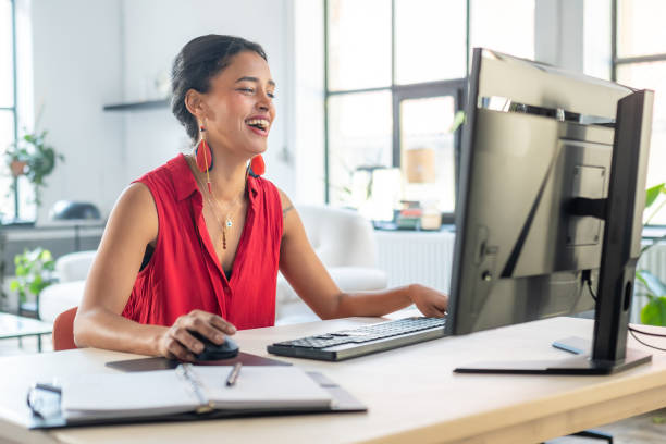 istock Cheerful Woman in Red Top Working on Desktop Computer 2203140290