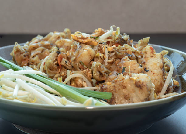 Fried thai noodle (pad thai) mix Stirred fried turnip cake or Fried radish cake (chai tow kway) served with bean sprout and chives in ceramic plate.