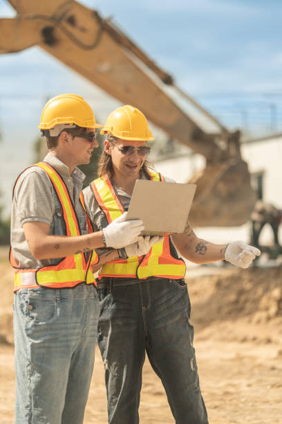 istock Workers in safety vests and helmets reviewing construction plans at a job site, highlighting teamwork, efficiency, and project execution for infrastructure and industrial development. 2203142034