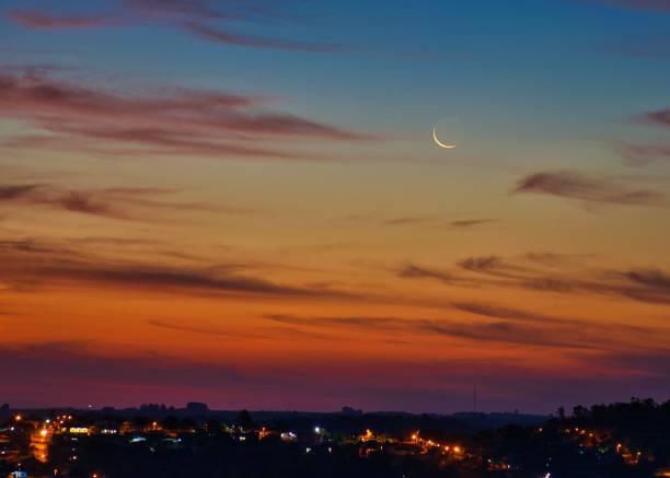 istock Cityscape at dusk with crescent moon 2203142110