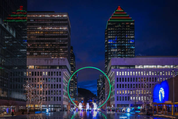 Captivating night scene of downtown Montreal, featuring the iconic Ring sculpture glowing green, with three illuminated polar bears below, festive holiday lights, Quebec, Canada (December 2024)