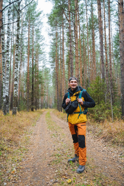 istock A solitary man with a sturdy backpack stands confidently on a winding dirt road through vibrant woods, surrounded by the breathtaking beauty of towering trees in a serene setting 2203149536