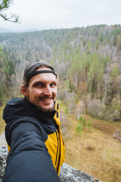 istock A man is happily taking a selfie while surrounded by the breathtaking mountains and natural landscape, enjoying his travel and leisure time in a beautiful forest while wearing a jacket 2203149537