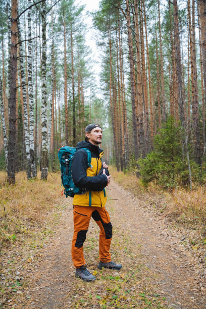 istock A man is standing on a winding dirt path surrounded by dense woods, wearing a backpack on his shoulders, taking in the serene and tranquil environment of nature all around him 2203149554