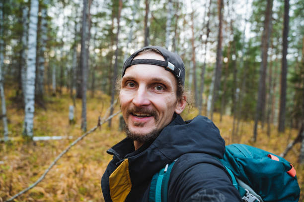 istock A joyful man with a bright and colorful backpack is happily capturing a selfie while immersed in the breathtaking beauty of the lush woods and the vibrant plants that surround him 2203149583