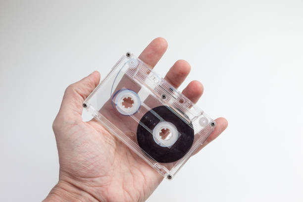 A close-up of a transparent retro cassette tape held gently by a human hand, evoking nostalgia and focusing on analog music media.