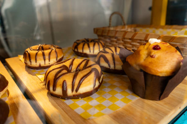 istock Donuts and cupcakes, displayed in a wooden showcase.  Chocolate, coffee, and white donuts 2203154411