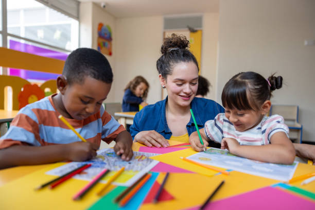 istock Preschool teacher supervising young students coloring in art class 2203154695