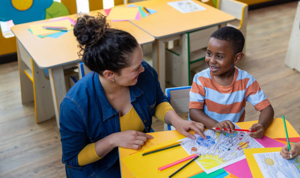 istock Preschool teacher talking to a boy in the classroom while coloring 2203154698