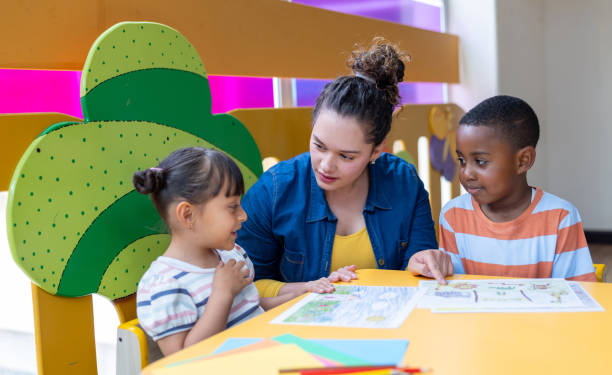 istock Teacher talking to elementary students while coloring at the kindergarten 2203154703