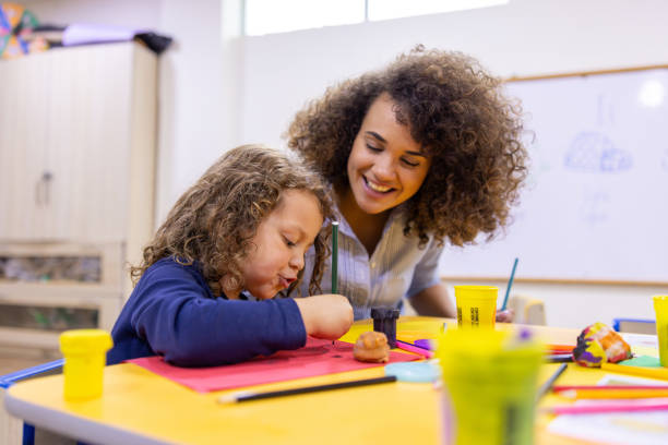 istock Happy kindergarten teacher coloring with a schoolboy in class 2203154720