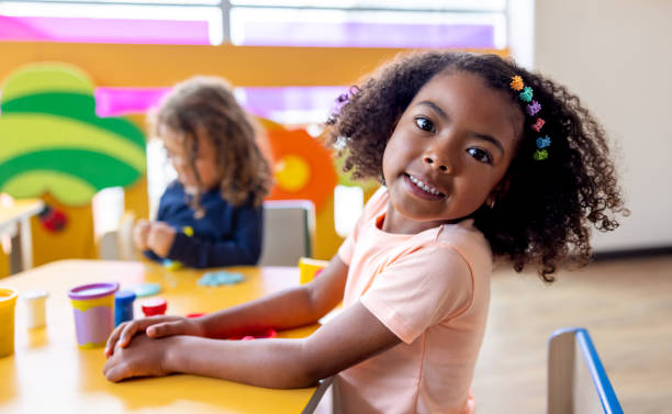 istock Happy girl smiling in the classroom while playing with clay 2203154727
