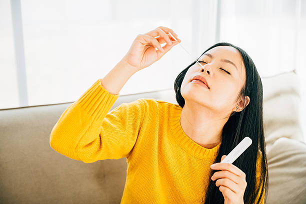 istock Woman at home uses a rapid antigen test kit inserting a swab into her nose 2203157065