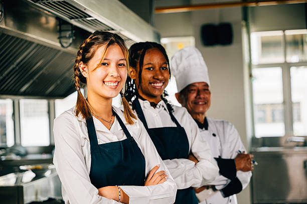 istock In a professional kitchen smiling chefs in uniform pose for a portrait. Displaying expertise togetherness and teamwork. Teaching colleagues working together. 2203157438