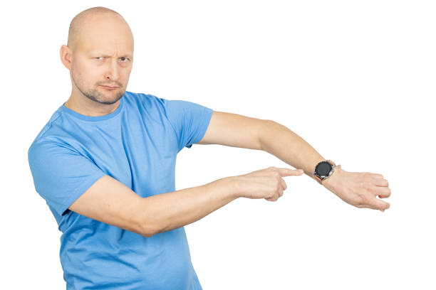 Bald man pointing at his smartwatch with an impatient expression