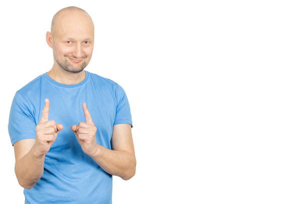 istock Smiling bald man pointing index fingers upwards on white background 2203159428