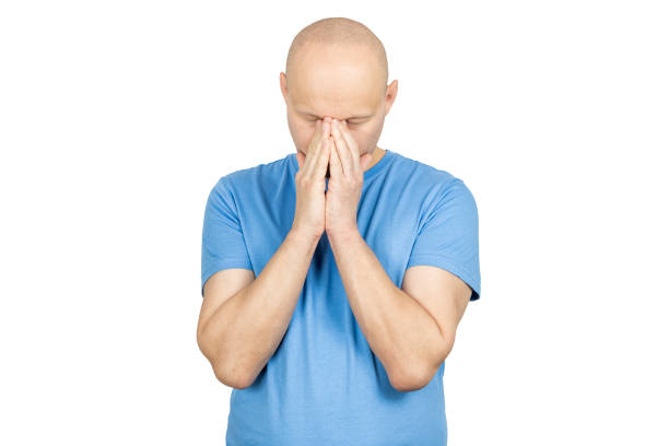 Bald man suffering from stress, covering face with hands, experiencing frustration and anxiety