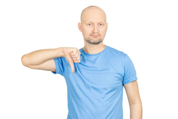 istock Bald man in blue t-shirt showing thumbs down gesture on white background 2203159810