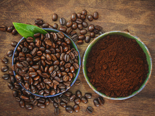 istock Coffee beans and ground powder on wooden background. 2203164359