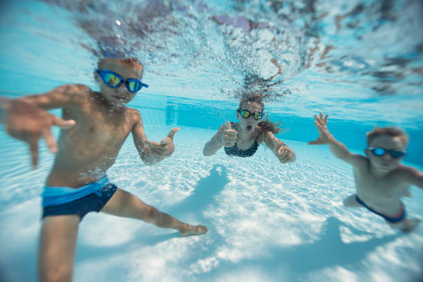 istock Three cute kids playing and dancing underwater in a pool 2203174711