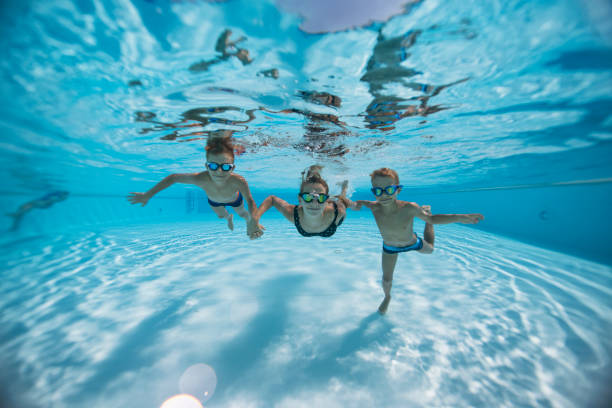 istock Three cute kids swimming underwater in a pool 2203174722