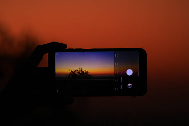 istock The image shows a hand holding a smartphone displaying a sunset photo being taken using the phone's camera app 2203175368