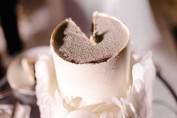 Close-up of a partially eaten wedding cake, featuring a white mousse texture and adorned with delicate feather-like decorations