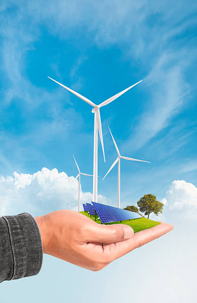 istock Hand holding solar panels and wind turbine against a blue sky. 2203184644