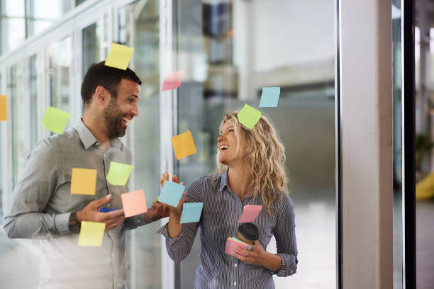 istock Happy entrepreneurs talking while making mind map on a glass wall in the office. 2203184758