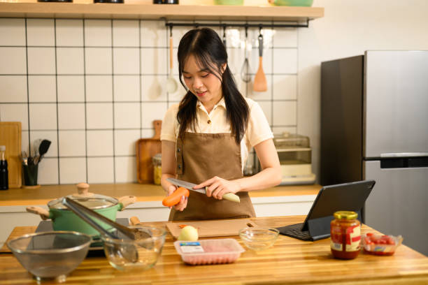 istock Pretty young woman preparing ingredients for spaghetti in a cozy kitchen 2203185879