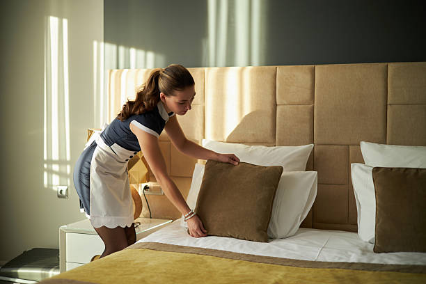 istock Hotel Housekeeper Arranging Pillows on Bed 2203186425